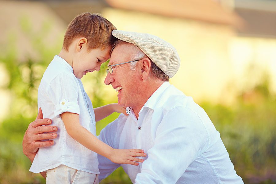 Life and Health Insurance - Portrait of Smiling Grandfather and Grandson Playing Together Outside on Sunny Day