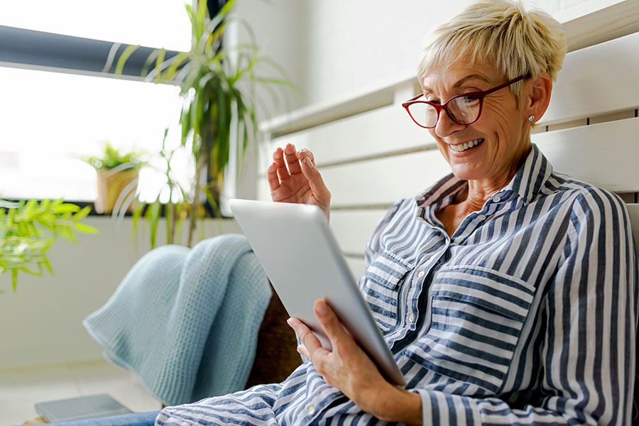 Resources - View of Smiling Mature Woman Sitting on Her Bed Using a Tablet